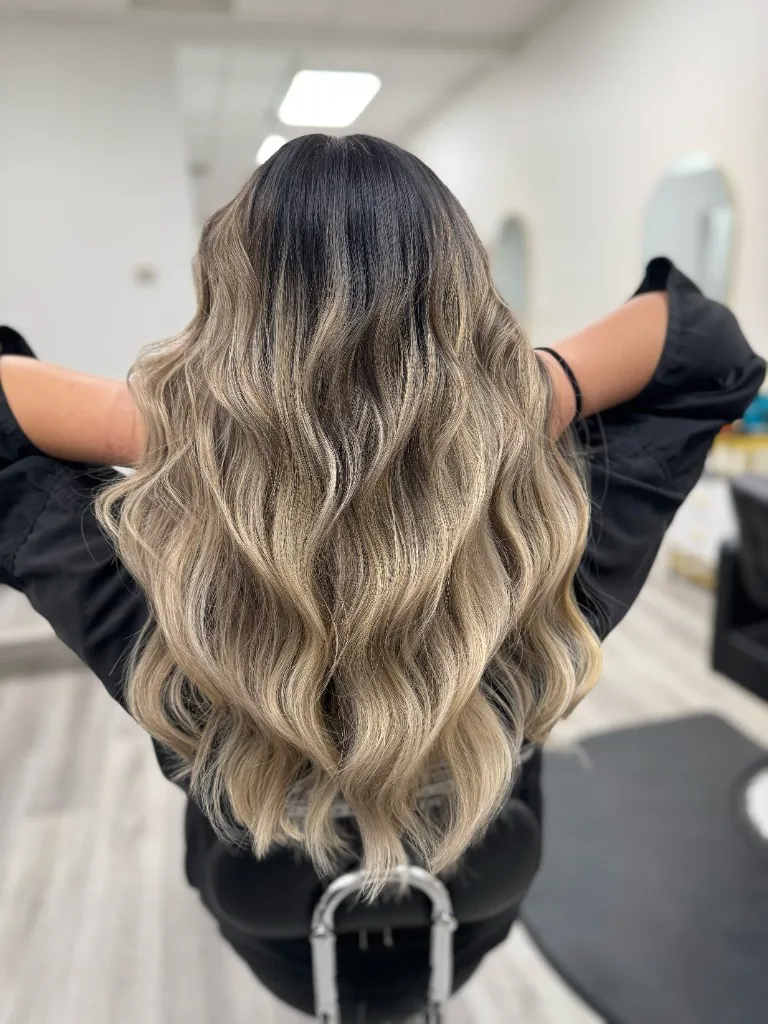Hand-painted balayage on long hair with soft caramel dimension and healthy shine, photographed at Emilie Hair Studio on Kingsway, Vancouver.